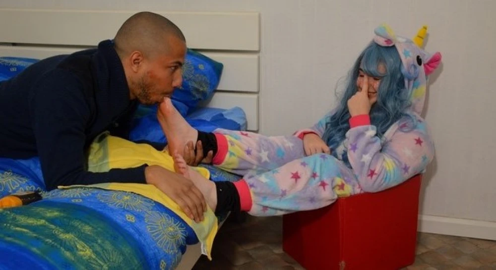 Estomy &amp; Bob45 - Jeune femme déguisée en licorne, assise sur un pouf de rangement, attendant que ses petits pieds soient dévorés 